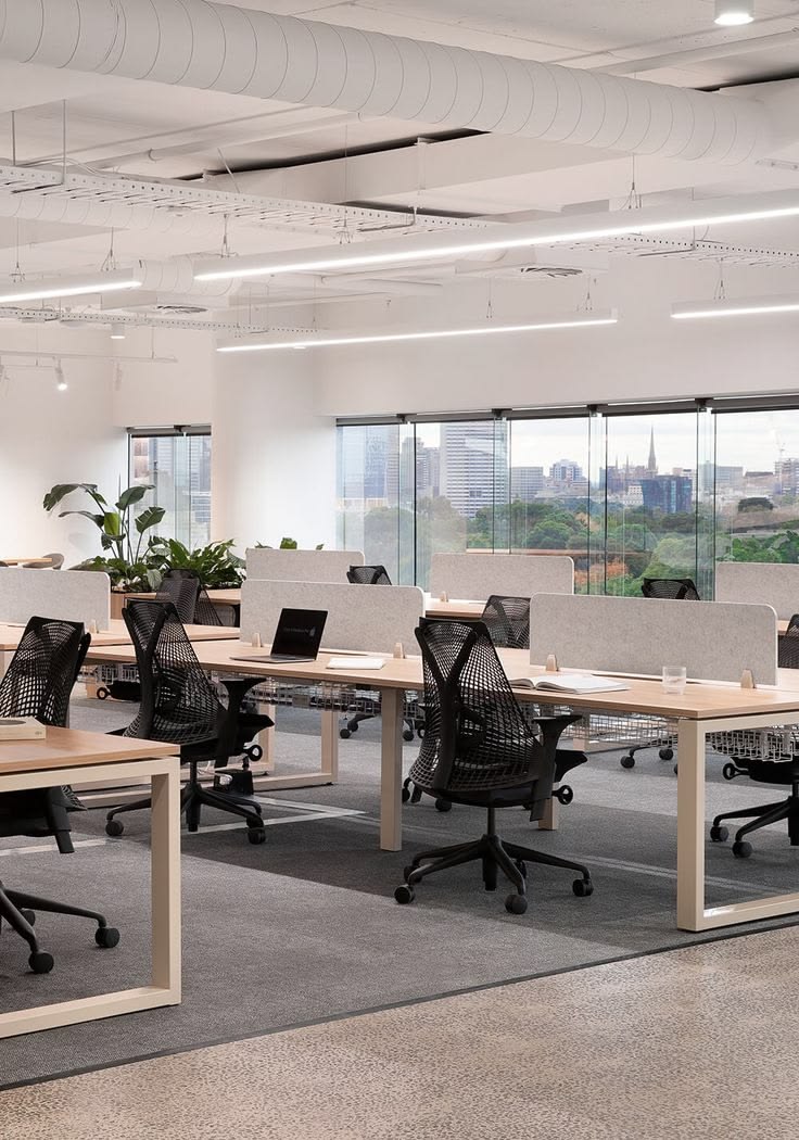 Open-plan office with adjustable desks and a clear walking path between work areas